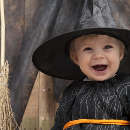 Kleinkind an Halloween mit Hexenkostüm.