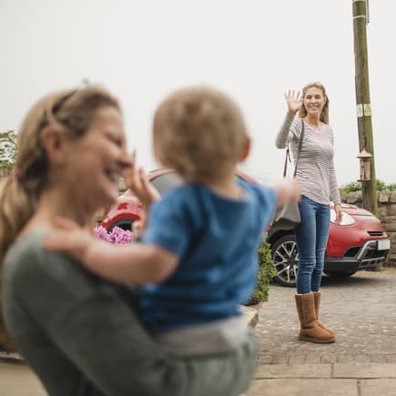 Nanny winkt mit Kleinkind der Mutter.