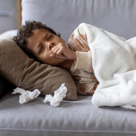 Krankes Kind liegt auf dem Sofa.