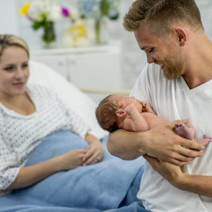 Vater hält sein neugeborenes Baby im Arm.