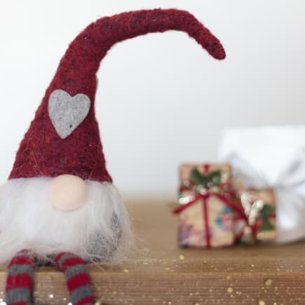 Wichtel sitzt vor Geschenken.