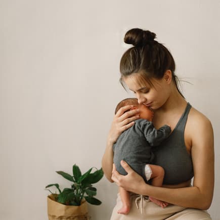 Mutter trägt Baby im Arm.