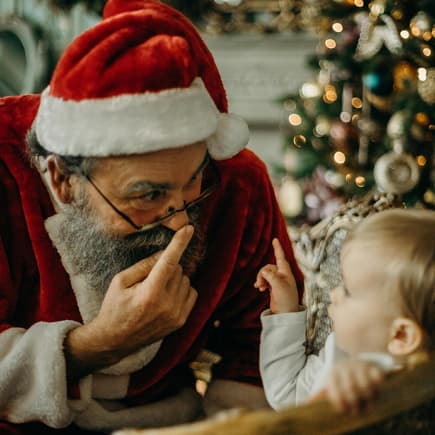 Weihnachtsmann spricht mit kleinem Kind.