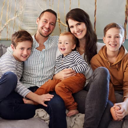 Familie mit drei Kindern sitzt auf dem Sofa.
