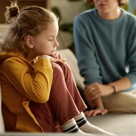 Mutter spricht ernst mit ihrem Kind auf dem Sofa.