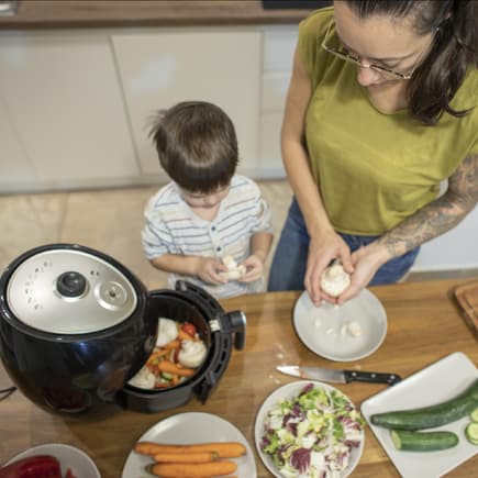 Mutter und Kind kochen mit dem Airfryer.