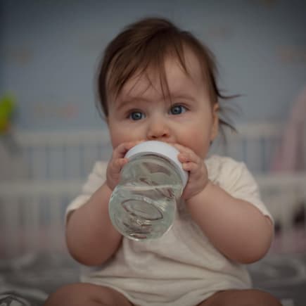 Baby trinkt aus Trinklernbecher.