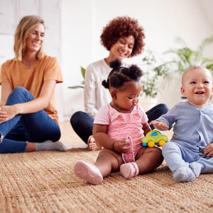 Zwei Mütter treffen sich zum Spielen mit Babys zu Hause.