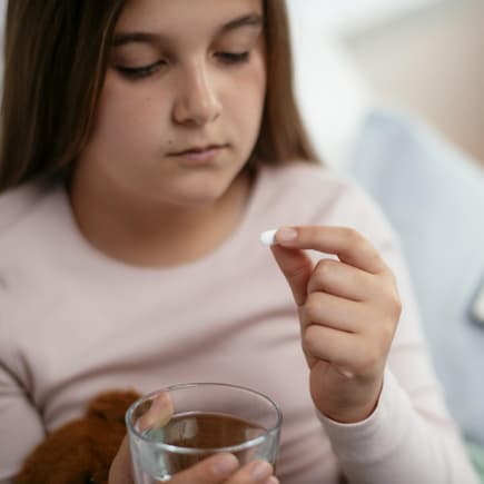Ein Mädchen nimmt eine Paracetamol Tablette. 