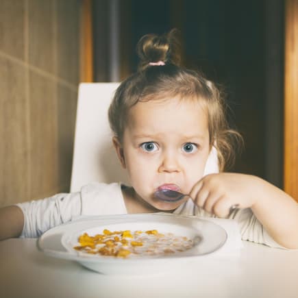 Kleines Mädchen isst Müsli.
