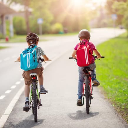 Zwei Schulkinder fahren nebeneinander Fahrrad.