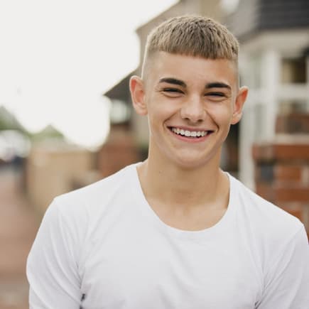 Junge mit Kurzhaarschnitt lacht in die Kamera.
