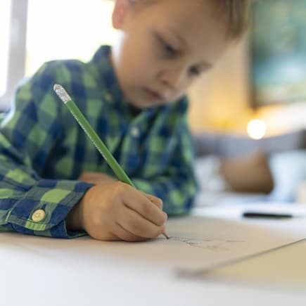 Kind zeichnet mit Bleistift.
