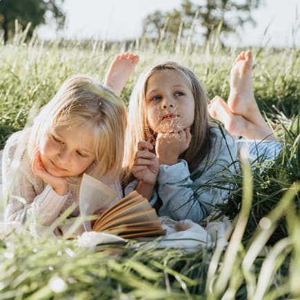 Zwei Mädchen liegen im Gras. 