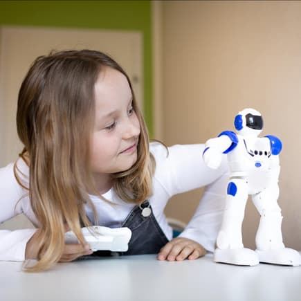 Mädchen spielt mit kleinem Roboter. 