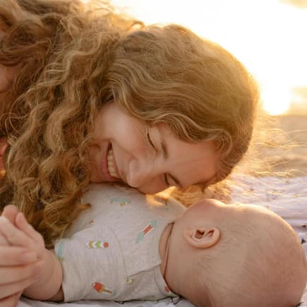 Glückliche Mutter legt am Strand ihren Kopf aufs Baby.