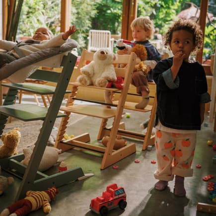 Baby und zwei Kinder spielen mit Tripp Trapp-Stühlen Zug.