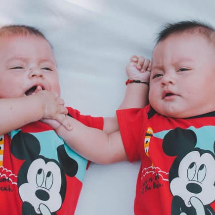 Zwillingsbabys mit Micky-Maus-Body