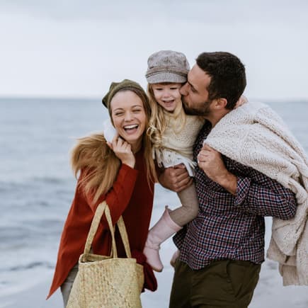 Mutter, Vater und Kind gehen am Strand spazieren.