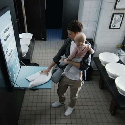 Ein mann wickelt sein Baby auf einer öffentlichen Toilette. 