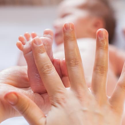 Mutter gibt Öl auf Babyfuß.