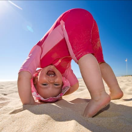 Ein Baby spielt in UV-Kleidung am Strand. 