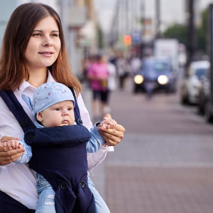 Eine Mutter trägt ihr Baby mit Blick nach vorne in der Trage 