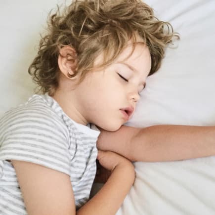 Kleines Kind schläft im Bett.