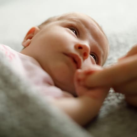 Müdes Baby hält Finger eines Elternteils.