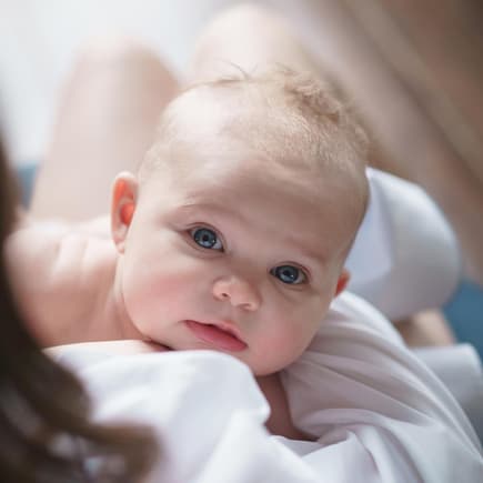 Kleines Baby schaut nach dem Stillen hoch.