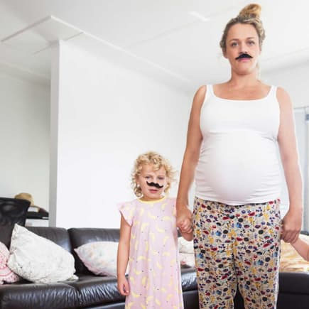 Schwangere Mutter mit zwei kleinen Kindern hat sich einen Schnurrbart aufgeklebt.