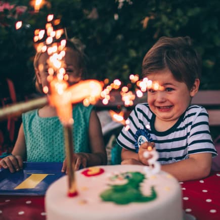 Kinder mit Geburtstagstorte mit Wunderkerze