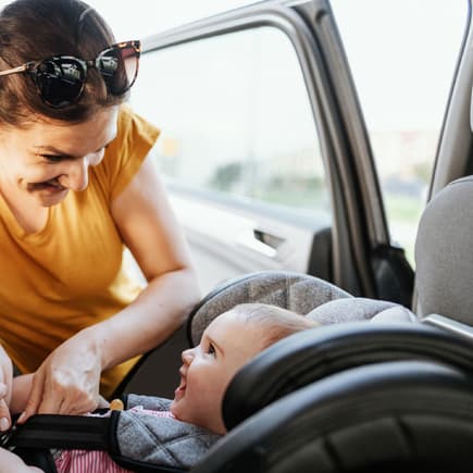 Eine Mutter schnallt ihr Baby im Auto an. 