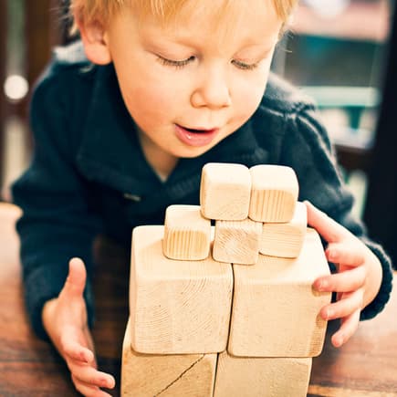Stein auf Stein: Bauklötze zählen zu den beliebtesten Spielzeugen überhaupt, fördern die Fantasie und die Kreativität. Kind mit Holzbausteinen