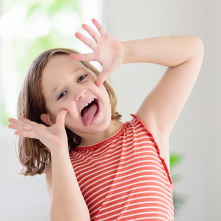 Lachen und Quatsch machen geht immer ... Dabei entwickelt sich der Humor von Kindern weiter. Kind schneidet eine Grimasse.