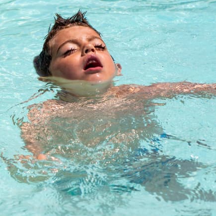 Junge mit geschlossenen Augen im Wasser.