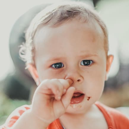 Kleinkind bohrt sich in der Nase.