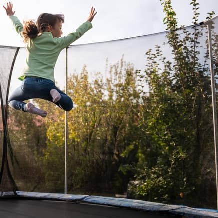 Kind springt hoch auf rundem Trampolin.
