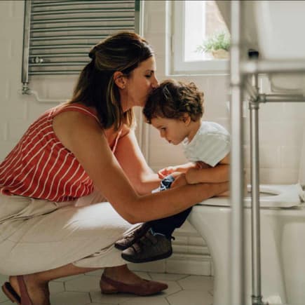 Mutter begleitet Kleinkind auf die Toilette.