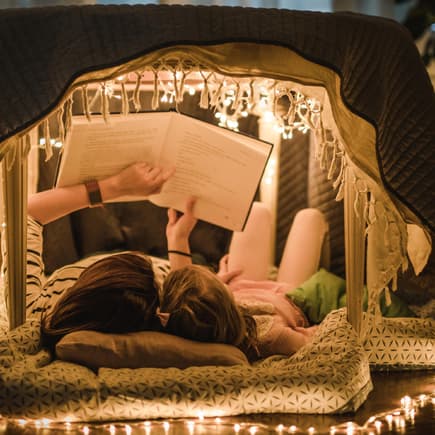 Mutter und Kind lesen Märchen in einer Höhle in der Wohnung.