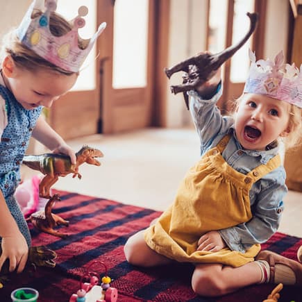 Zwei kleine Kinder spielen mit Dino-Figuren.