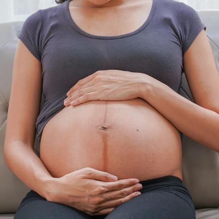 Eine schwangere Frau mit Linea Negra auf dem Babybauch. 