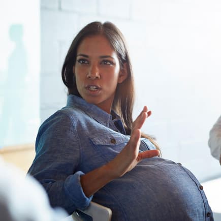 Schwangere Frau erzählt in der Runde.