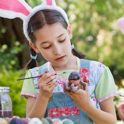 Zwei Kinder bemalen Ostereier im Garten.