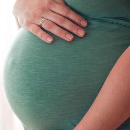 Eine schwangere Frau hält eine Hand auf ihren Babybauch.