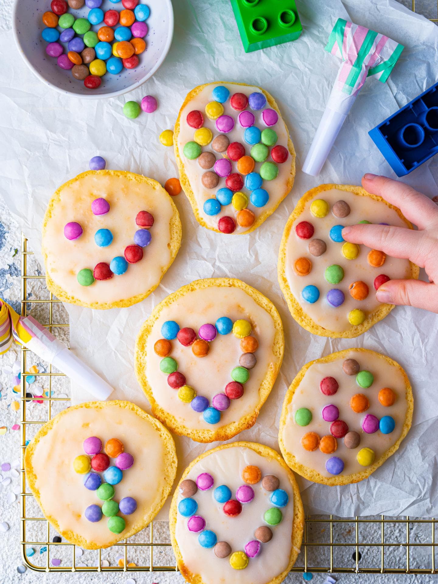 Fantakuchen als Mini-Amerikaner liegen mit Smarties verziert auf dem Backblech.