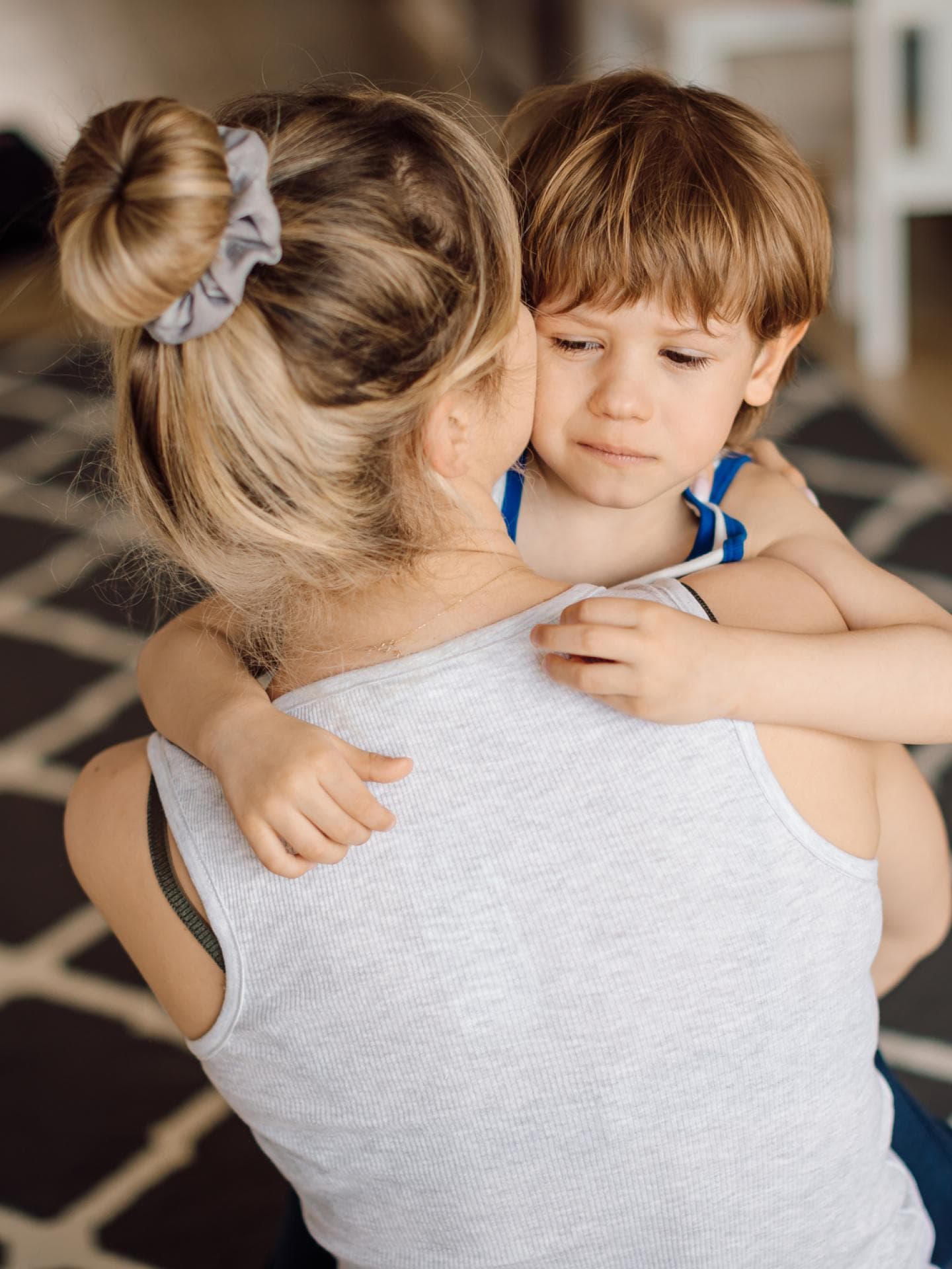 Ein kleiner Junge lässt sich von seiner Mutter in den Arm nehmen, um getröstet zu werden. 