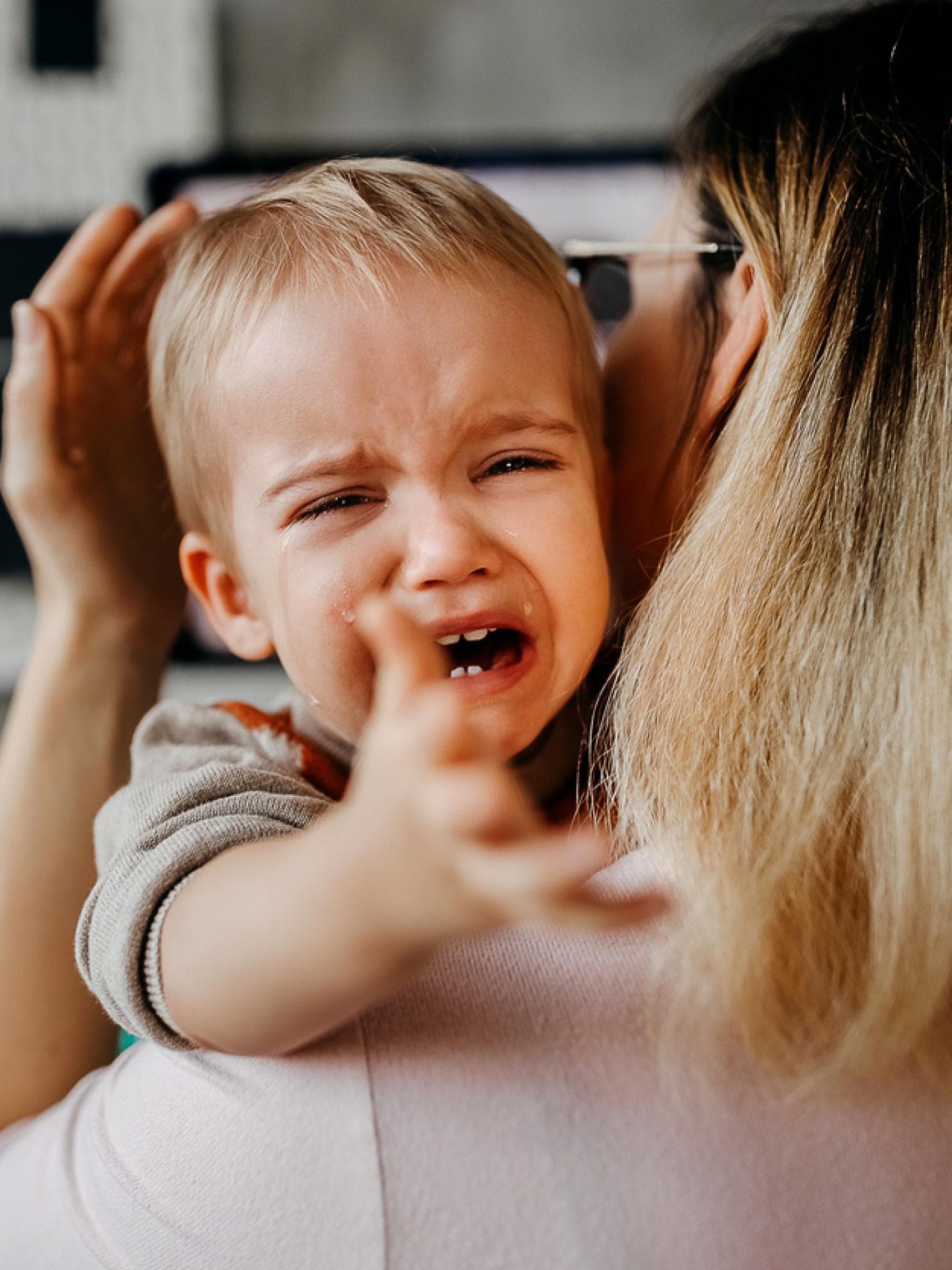 Ein kleines Kind wird bei einem Wutanfall von seiner Mama auf den Arm genommen und getröstet.
