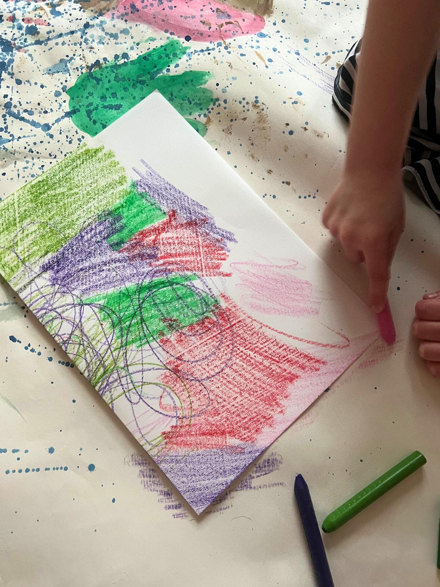 Papier wird mit Wachsmalstiften bunt bemalt