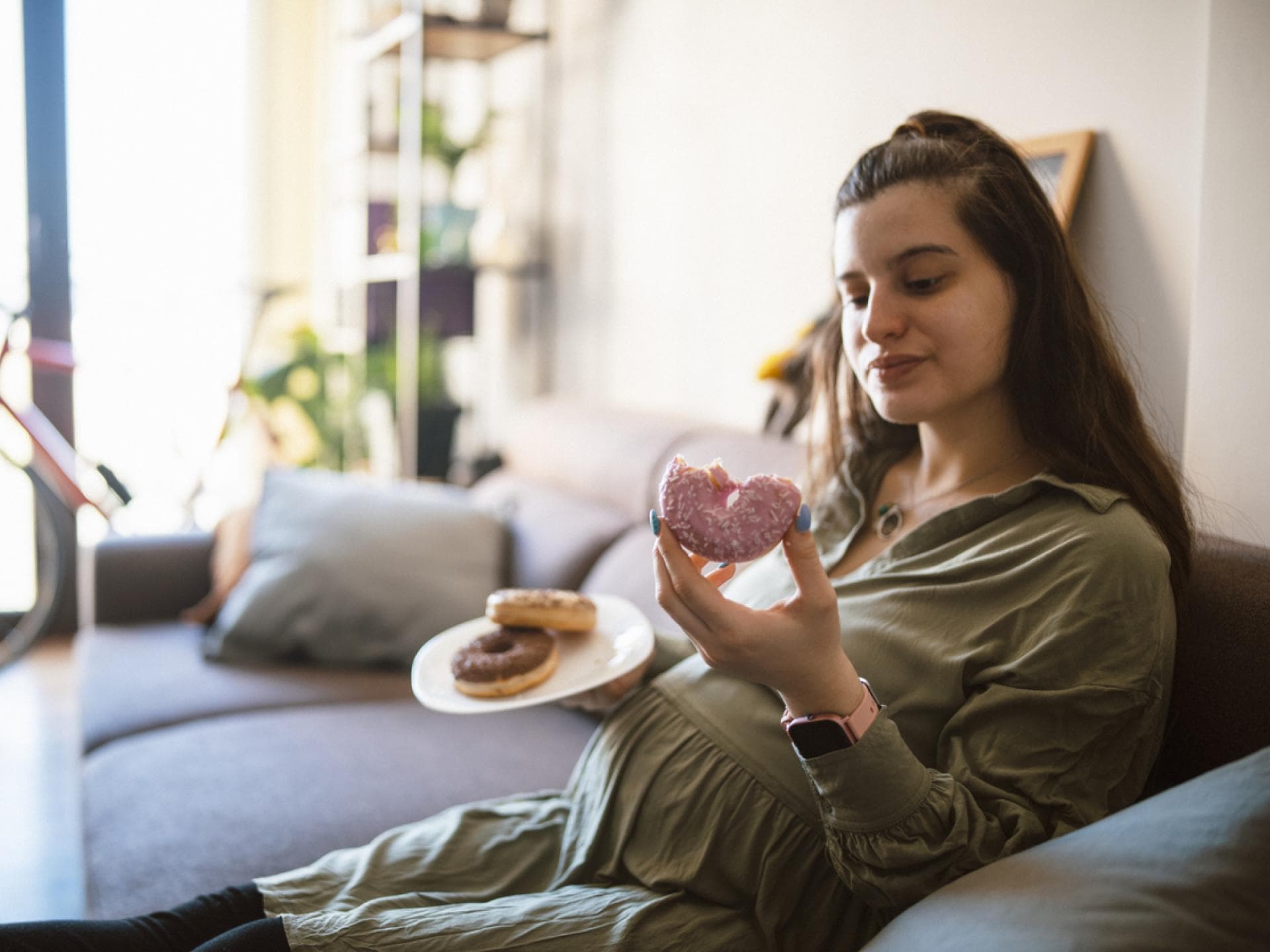 Zu viel Zucker in der Schwangerschaft kann sich negativ auswirken. Eine Frau isst Donuts in der Schwangerschaft